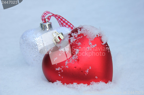 Image of Red and white heart ornaments in snow