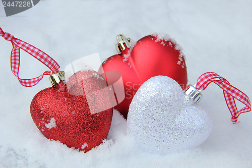 Image of Red and white heart ornaments in snow