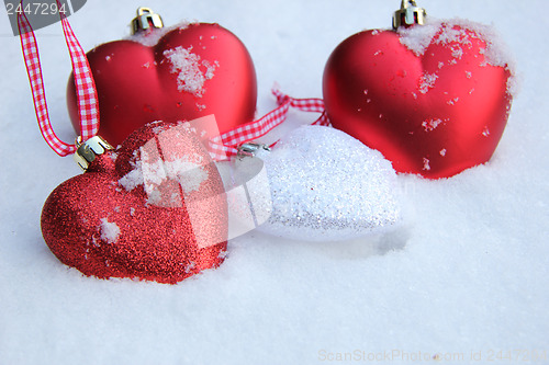 Image of Red and white heart ornaments in snow