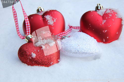 Image of Red and white heart ornaments in snow