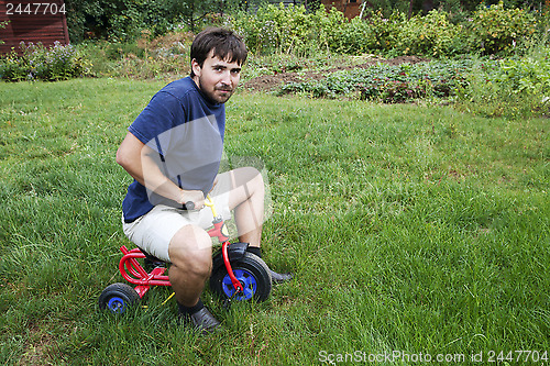 Image of Adult man on a small tricycle