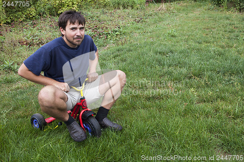 Image of Adult man on a small tricycle