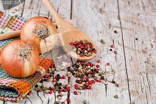 Image of fresh onions and peppercorns in a spoon 