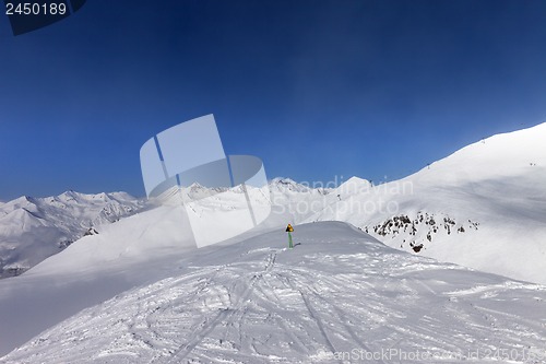 Image of Warning sing on ski slope and snowy mountains in sun day