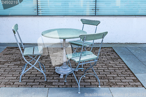 Image of Table and three chairs in an outdoor cafe