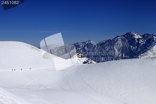 Image of Snowboarders move on footpath to off piste slope at sun day