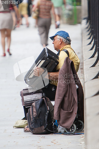 Image of PARIS, FRANCE - JULY 27, 2013: An accordion player sitting on a 