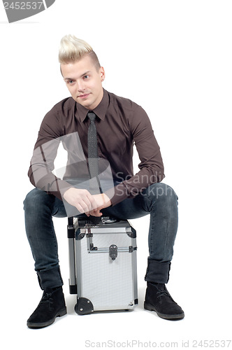 Image of Handsome man sitting on the suitcase