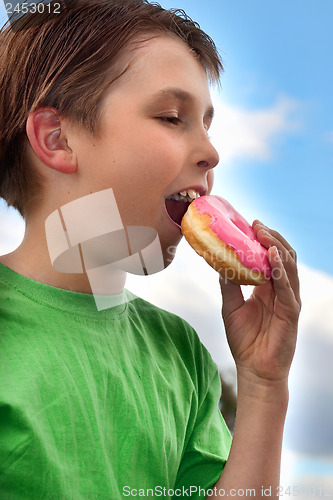 Image of Boy biting a yummy pink iced doughnut (donut)