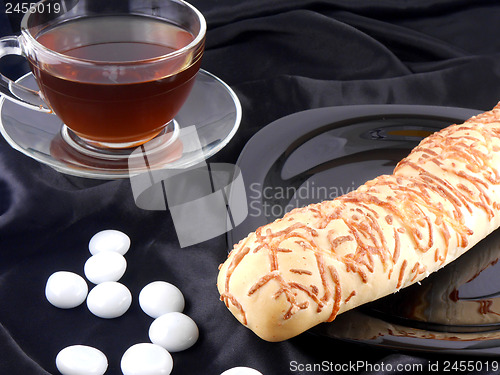 Image of Hot tea with cheese bread and white stones on black background