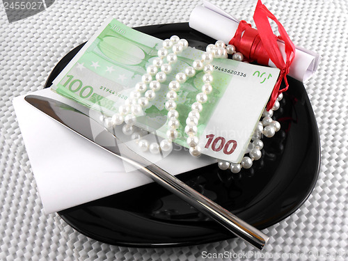 Image of Money on plate, knife, diamonds and gift bow on white paper