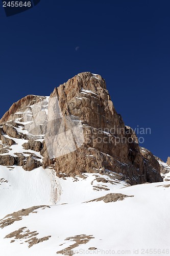 Image of Snowy rock and cloudless sky with moon