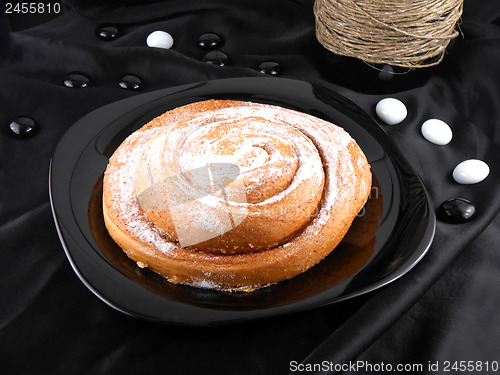 Image of sweet cake on black background, white stones and wine bottle