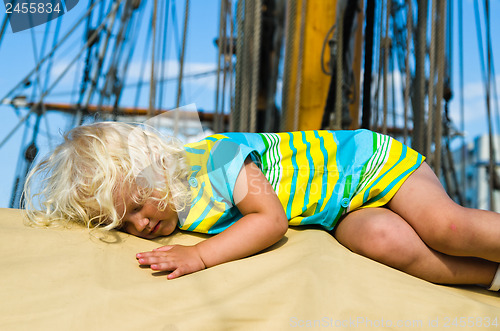 Image of the little girl fell asleep on the deck of a sailboat  