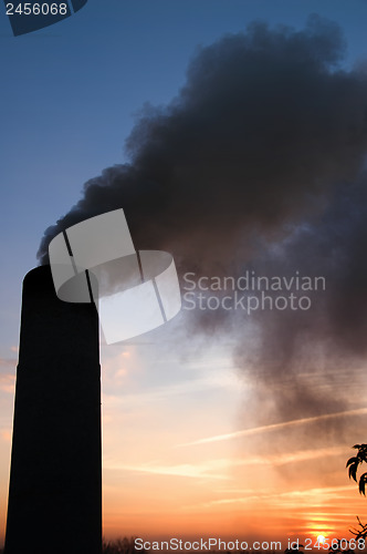 Image of smokestack over sunset and blue sky