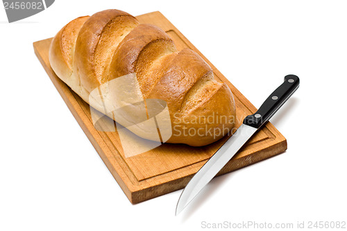 Image of fresh natural bread with knife on breadboard