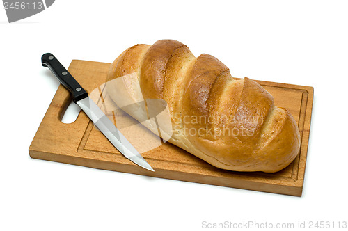 Image of fresh natural bread with knife on breadboard