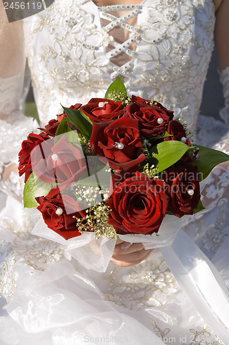 Image of red roses bouquet in married woman's hand