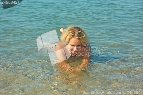 Image of Teenage girl lies in shallow seawater