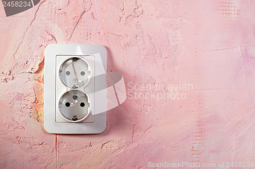 Image of White socket on pink wall