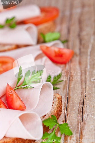 Image of bread with sliced ham, fresh tomatoes and parsley