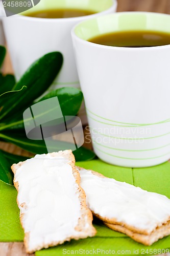 Image of two cups of tea and crackers with cream cheese