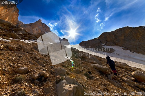 Image of Weary hiker ascent to mountain pass in evening