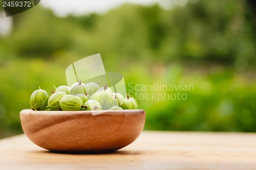 Image of Close-Up Of Gooseberries In Vintage Wooden Bowl On Wooden Table