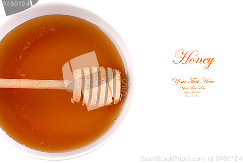 Image of Closeup of a bowl of amber honey with a honey wand isolated on w