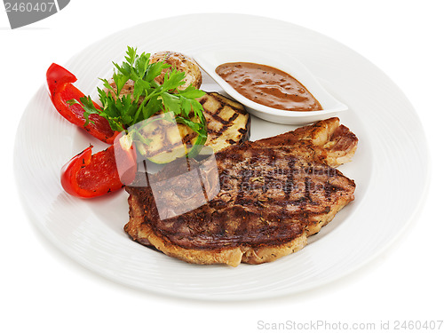 Image of Grilled steaks, baked potatoes and vegetables on white plate.