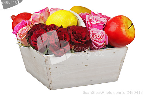 Image of Flower arrangement of red roses and fruits in wooden basket isol