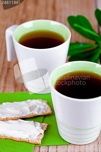 Image of two cups of tea and crackers with cream cheese 