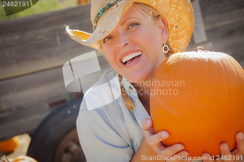 Image of Beautiful Blond Female Rancher Wearing Cowboy Hat Holds a Pumpki