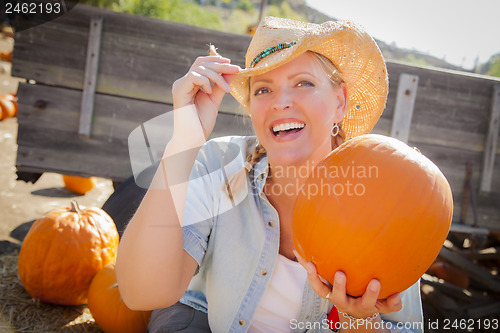 Image of Beautiful Blond Female Rancher Wearing Cowboy Hat Holds a Pumpki