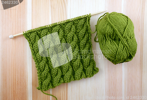 Image of Green cable stitch knitting with a ball of yarn