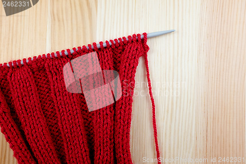 Image of Red knitting on the needle in rib stitch