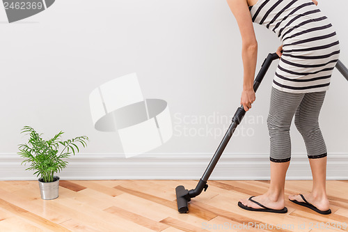 Image of Woman vacuum cleaning the room