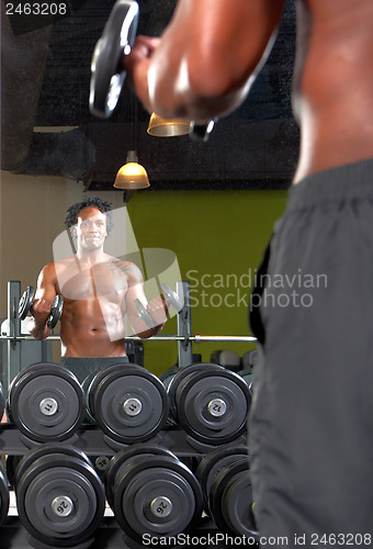 Image of Mirror reflection of two men exercising in gym