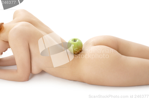 Image of naked redhead with green apple on her spine