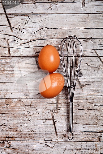 Image of wire whisk and two brown eggs