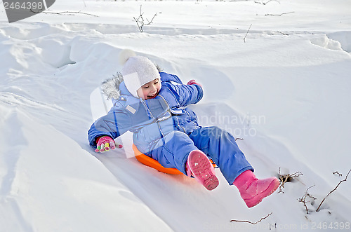 Image of Little girl on a sled sliding on snow