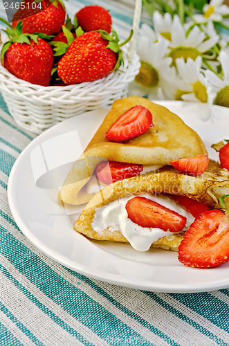 Image of Pancakes with strawberries and basket with berries on a napkin