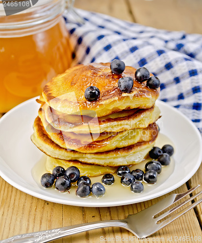 Image of Flapjacks with blueberries and a jar of honey on the board