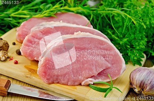 Image of Meat pork slices on a board with greens