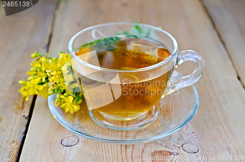 Image of Herbal tea from tutsan in a glass cup on a board