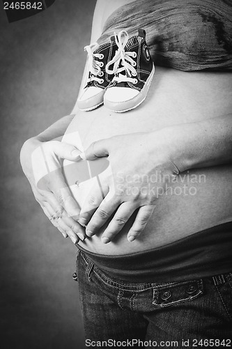 Image of pregnant woman with a child shoe and hand heart shape