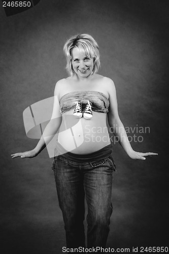 Image of beautiful pregnant woman with child boots on her tummy