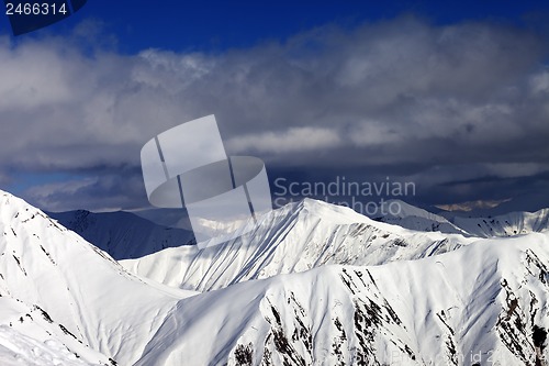 Image of Snowy sunlit mountains and cloudy sky