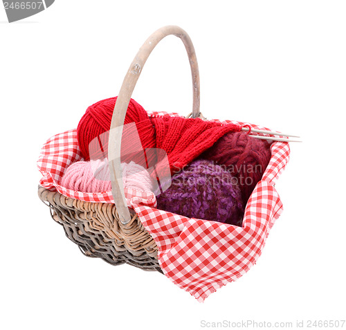 Image of Pink, purple and red yarn with knitting in a basket