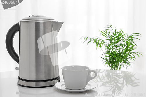 Image of White cup and electric kettle on the table